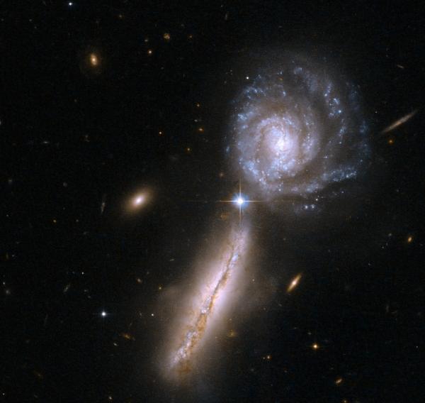 Сталкивающиеся галактики ориентированы почти перпендикулярно. После столкновения материал одной в значительной степени захватывается более массивной галактикой и затем вращается вокруг неё. (Здесь и ниже илл. NASA, ESA, Hubble Heritage.)